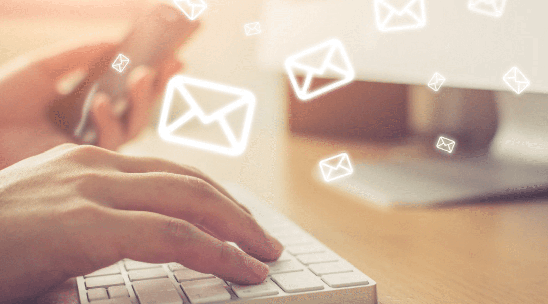 womans hand on a white keyboards with a few white outline envelopes flying away